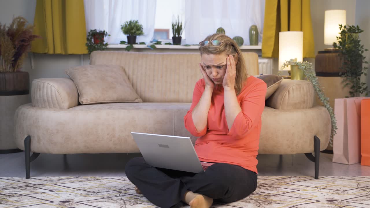 mujer cerrando la computadora portátil con expresión de enojo.