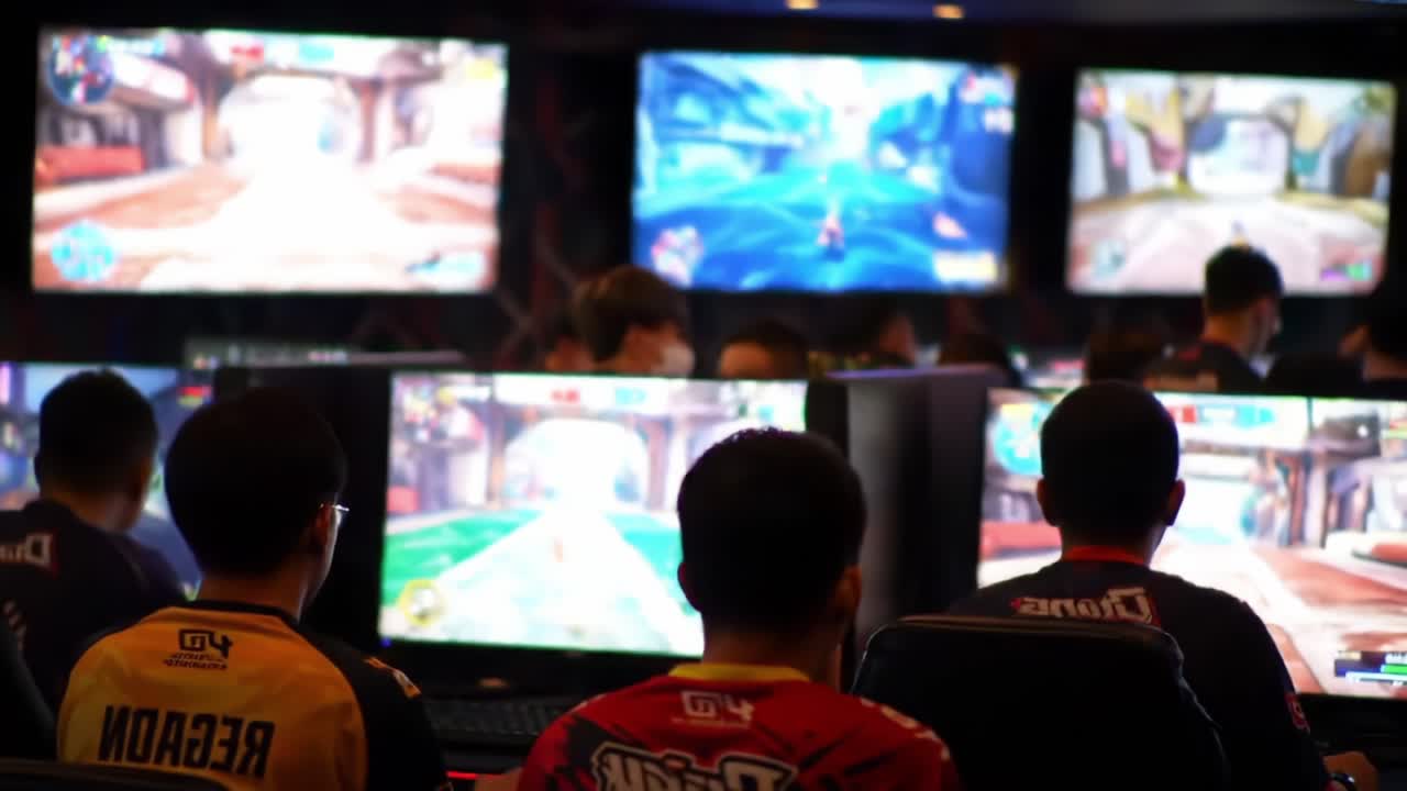 Intense Gaming Session: A Competitive E-Sports Tournament Featuring Players Engrossed in Gameplay with Multiple Monitors Displaying Action-Packed Scenes