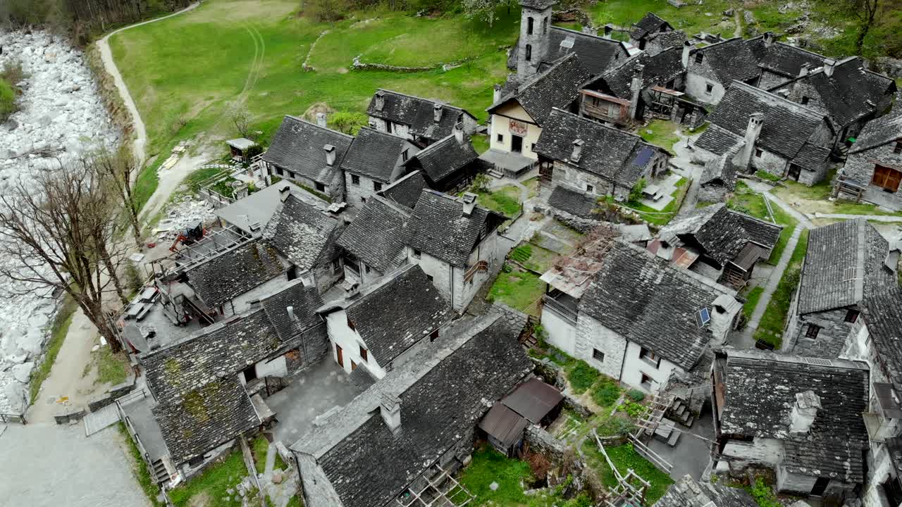 sobrevuelo aéreo sobre el pueblo de foroglio en ticino, suiza con un movimiento panorámico desde los tejados de la antigua casa de piedra hasta la cascada