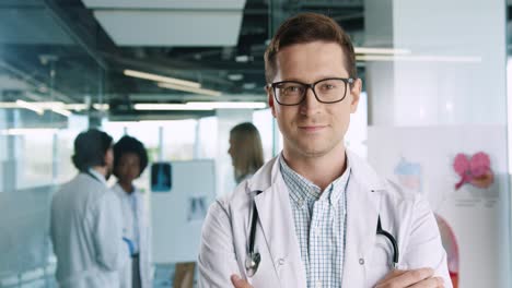 caucasian male doctor wearing glasses looking at camera in hospital office