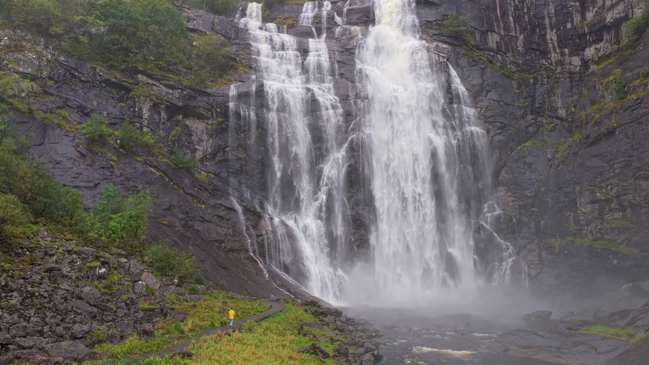 Toma aérea de la cascada Skjervefossen con un hombre solitario debajo, Noruega