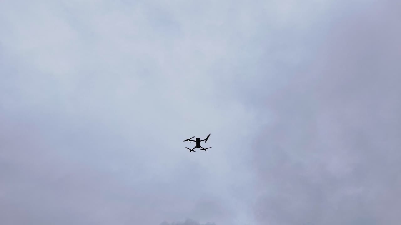 Fast spinning propellers on hovering drone, cloudy sky in Czechia