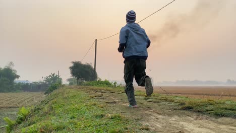 man jogging at rural road during sunrise, gas plant smoke polluting environment