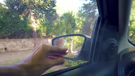 escena de espera, mano de humo enrollado cigarrillo sobre exuberante paisaje verde natural, dentro de un punto de vista de coche, fumar desde la ventana en la parada, momento de relajación