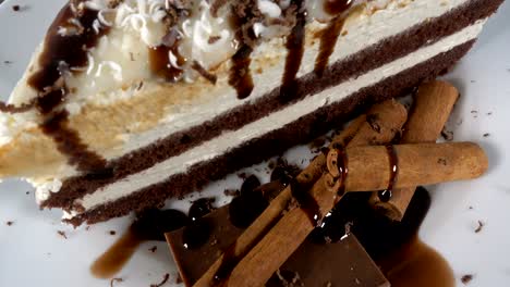 una rebanada de pastel de chocolate con chocolate y canela en un plato blanco giratorio, 4k