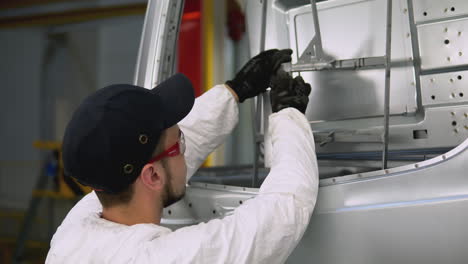 trabajador de la fábrica inspeccionando una parte de la carrocería del autobús