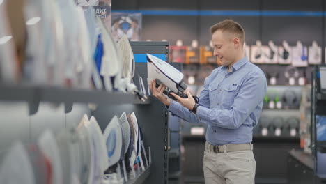 a young handsome man examines the iron in the store to buy a new apartment. evaluates the usability