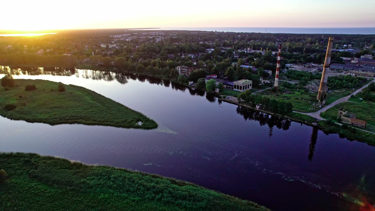 Sunset over the river in Latvia showcasing lush landscapes and buildings