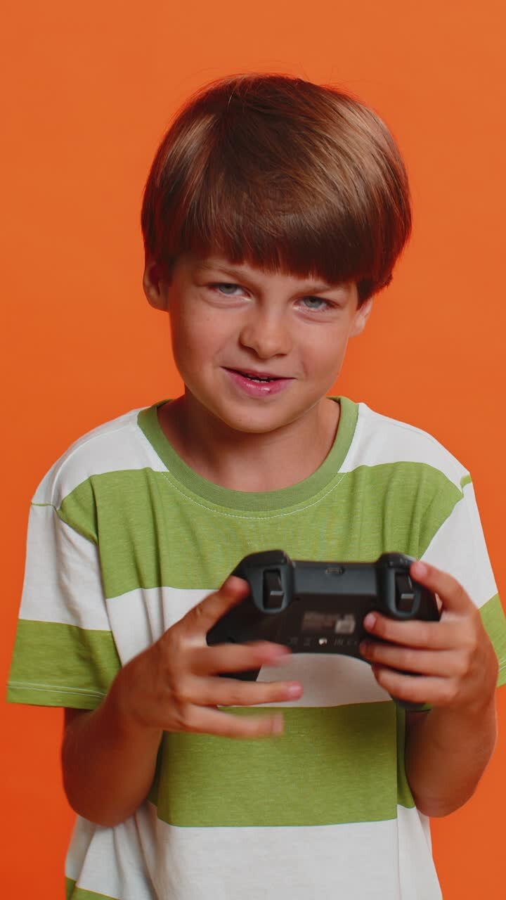 Child boy using joystick controller playing video console television game enjoying success winning