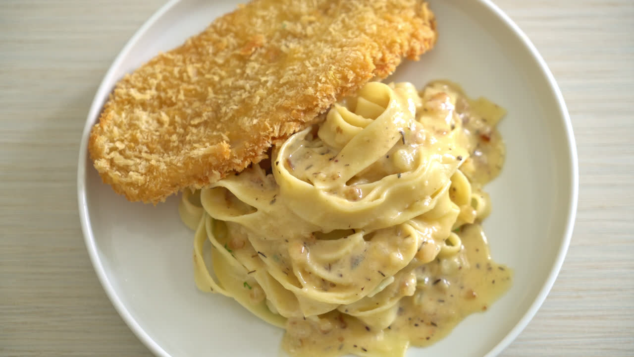 Pasta fettuccine casera con salsa de crema blanca y pescado frito