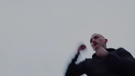 hero shot of a driven young man shadowboxing against a gray sky