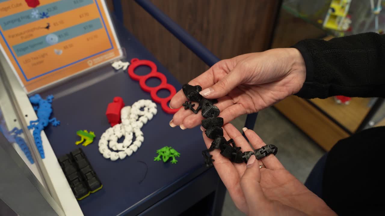 dama mostrando un lagarto de plástico en una colección de artículos hechos a mano en una impresora 3d