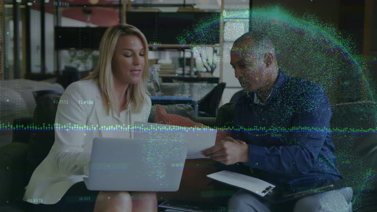 Man sliding paper, woman glancing laptop, both pointing, typing, nodding in business review