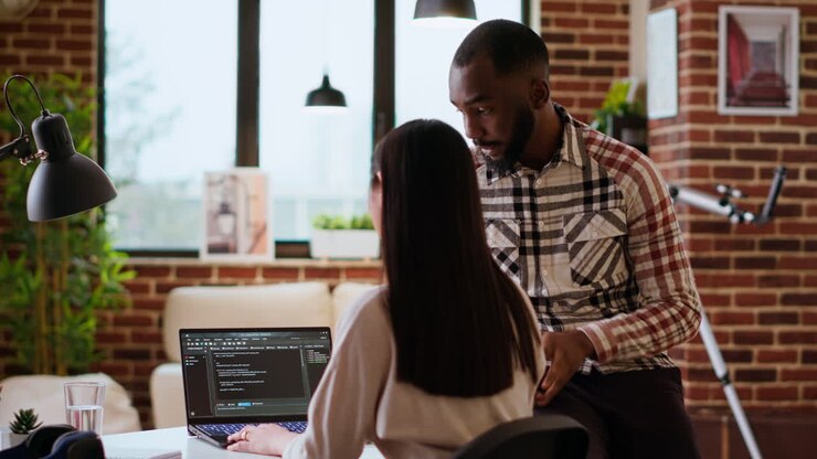 Interracial creative team programing code on a laptop and debugging