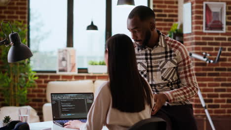 interracial creative team programing code on a laptop and debugging