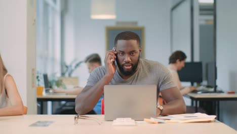 Angry-man-talking-on-mobile-phone-at-coworking-space.-Aggressive-guy-call-phone