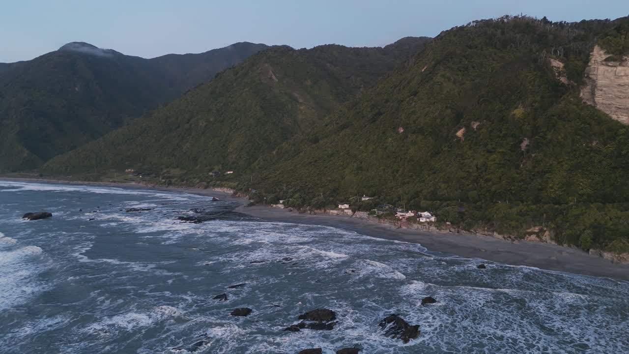 Aerial View of a Coastal Beach with Mountains and Forest