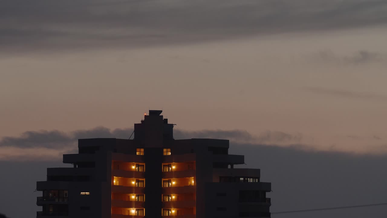 Solnedgang timelapse af en elevator på taget af et højhus hotel med gylden bysilhuet i baggrunden, plads til tekst.