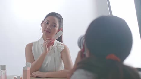 behind the scenes on photo shoot: beautiful asian model poses for a photographer, she takes photos with professional camera