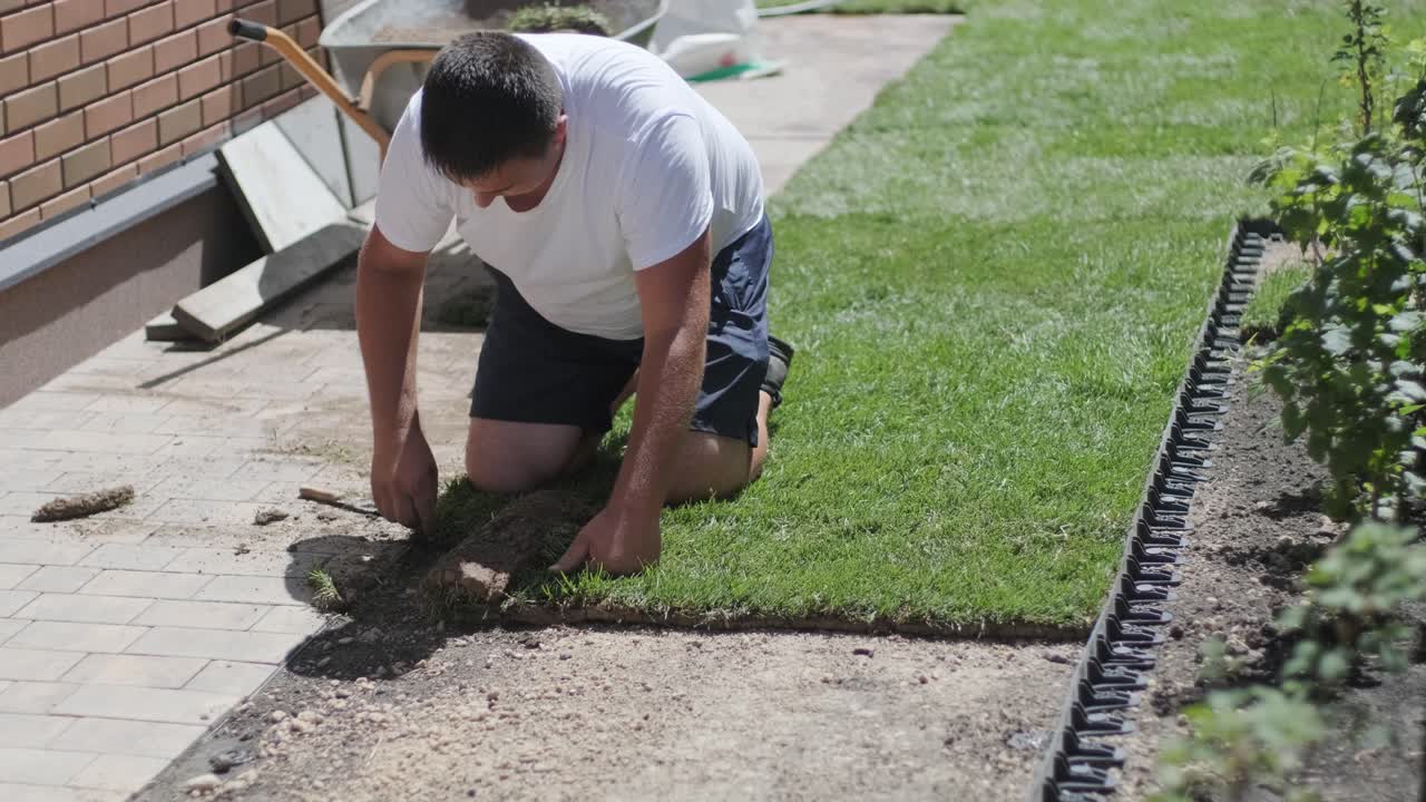 jardinero colocando césped en el patio privado con valla de madera