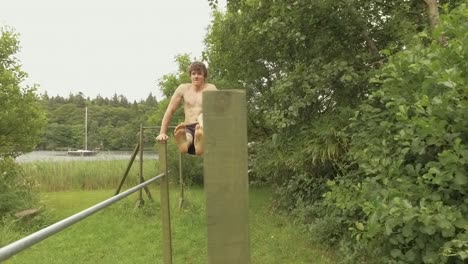 fit young man performs l-sit core strength exercise on parallel posts