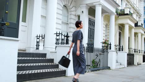 stylish woman carrying bag walks along city street