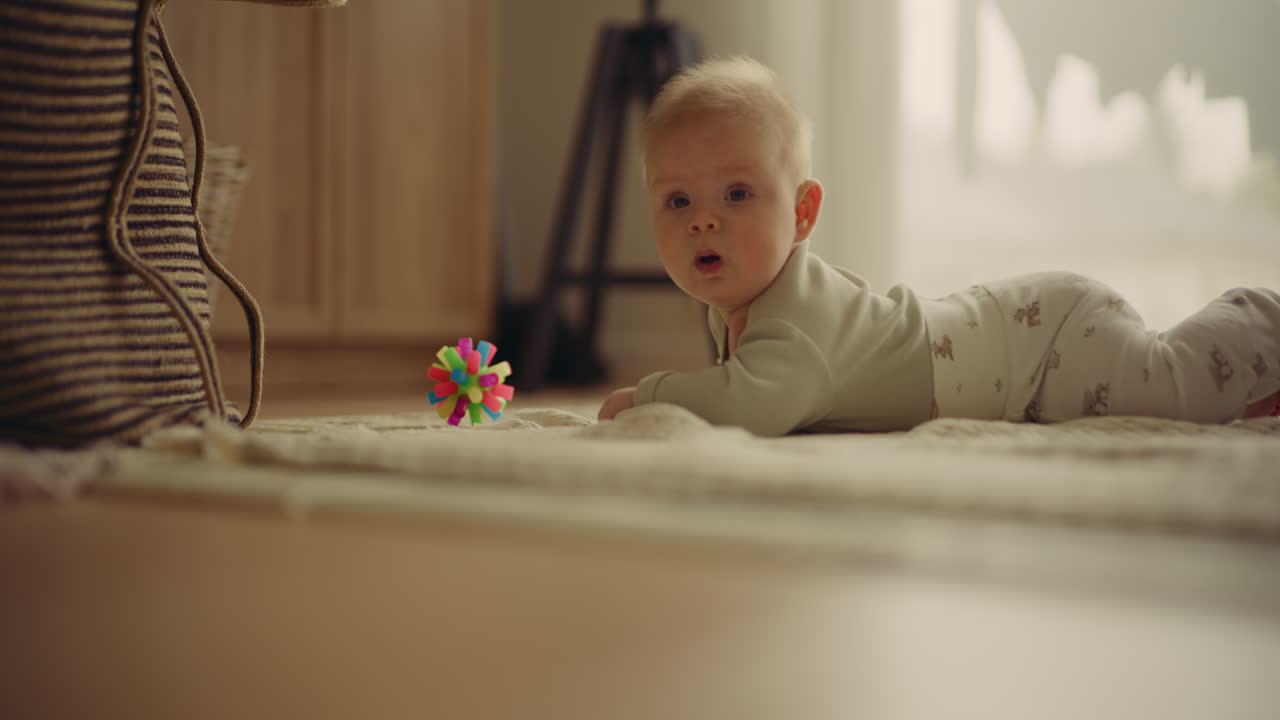 Baby lying on a carpet looking at a toy