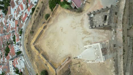 Vertikales-Video-Der-Freizügigen-Burg-Mourao-Mit-Stadtbild-Im-Hintergrund,-Zurückgezogener-Und-Nach-Oben-Geneigter-Aufnahme-Aus-Der-Luft