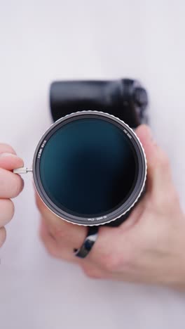 vertical - person hold camera with variable nd filter and adjust light intensity