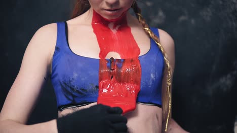 bizarre girl in a swimsuit draws a line with brush and red paint from the neck down below. close up