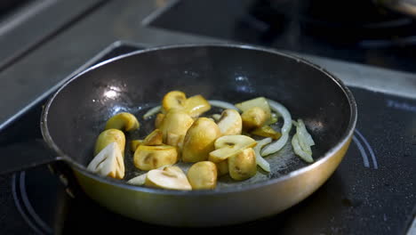 cooking mushrooms in frying pan. delicious mushrooms are frying with onions in oil on a stove. close-up.