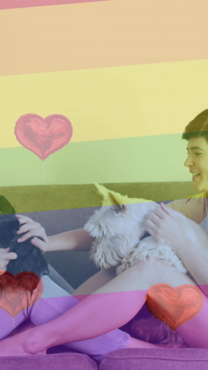 Animation of heart emojis and rainbow flag over caucasian female couple with dogs