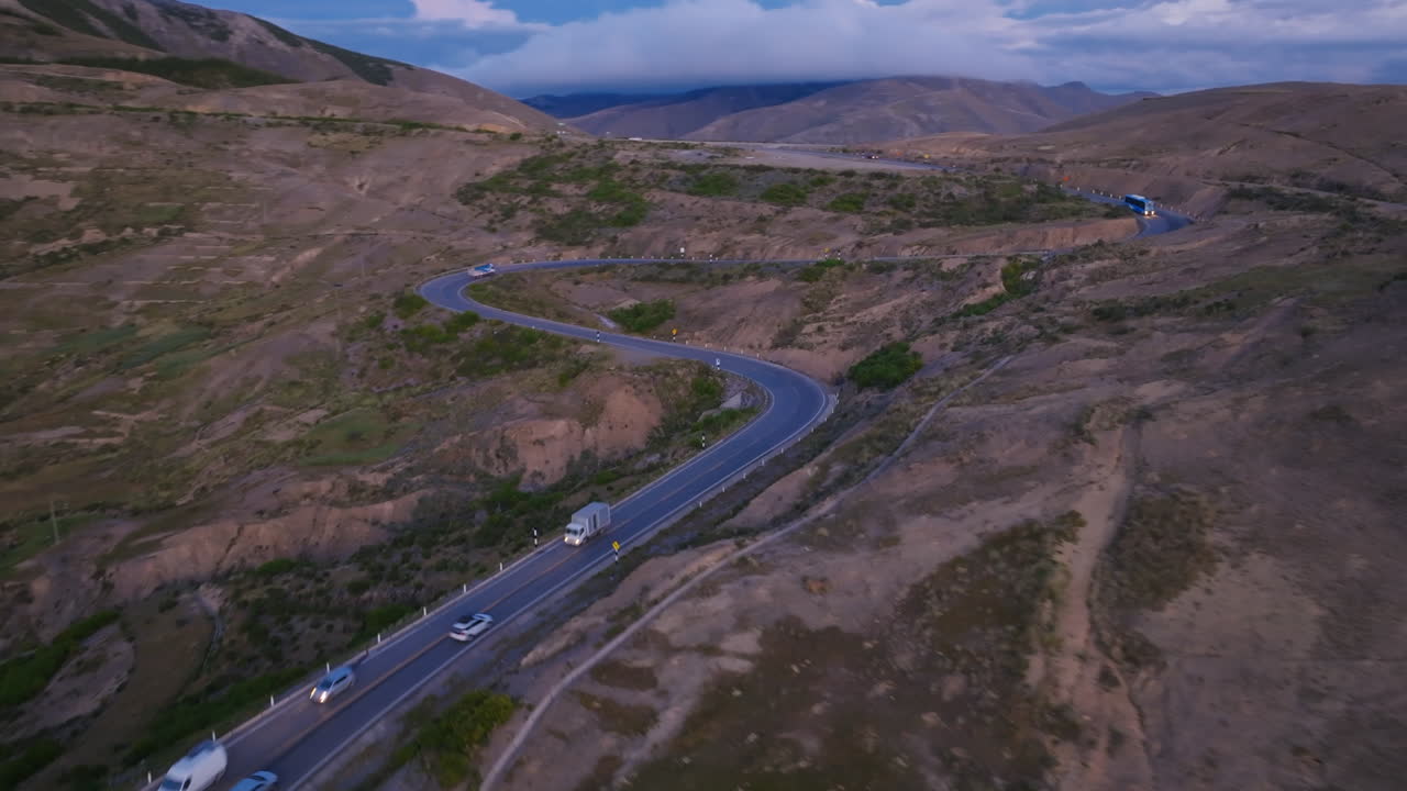 imágenes aéreas durante la puesta de sol siguiendo coches que viajan a lo largo de una carretera montañosa en perú