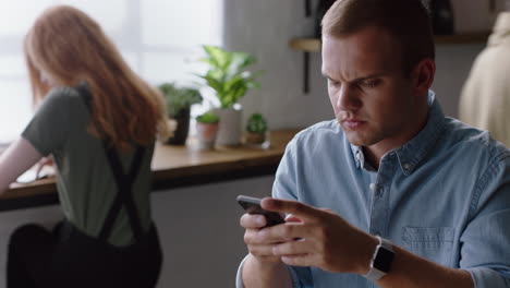 Joven-Hombre-De-Negocios-Usando-Un-Teléfono-Inteligente-En-Una-Cafetería-Tomando-Café-Navegando-En-Línea-Leyendo-Mensajes-De-Correo-Electrónico-En-Un-Teléfono-Móvil-Enviando-Mensajes-SMS-Disfrutando-De-La-Comunicación-Por-Teléfono-Celular