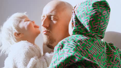 children kissing their father in living room 4k