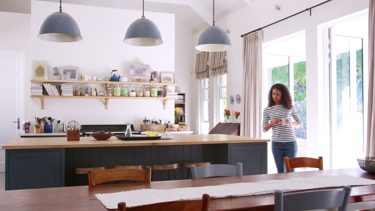 Donna di etnia mista che beve caffè in una cucina open space
