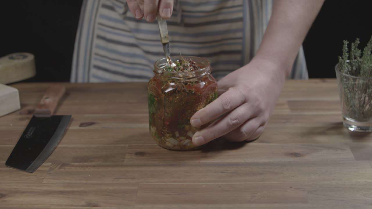 Stirring chimichurri sauce in a jar. Argentinian gastronomy