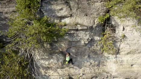 girl rock climber scaling an outdoor rock wall cliff - adventure sports - extreme sports - action sports - rock climbing
