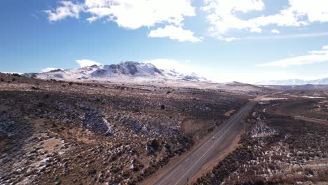 vista aérea del viaje por carretera de epica en sierra nevada con paisaje de montañas nevadas y carretera asfaltada con autos conduciendo rápido