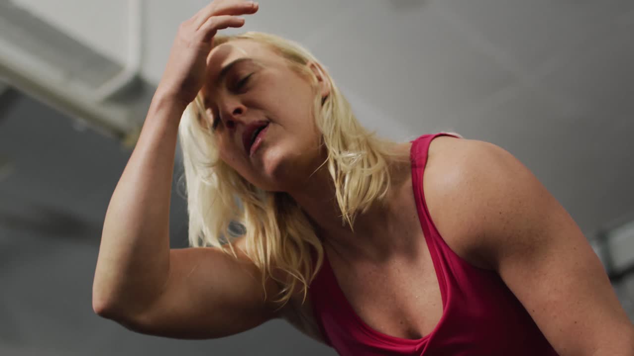 Donna caucasica in forma, stanca, che si prende una pausa dall'allenamento in palestra