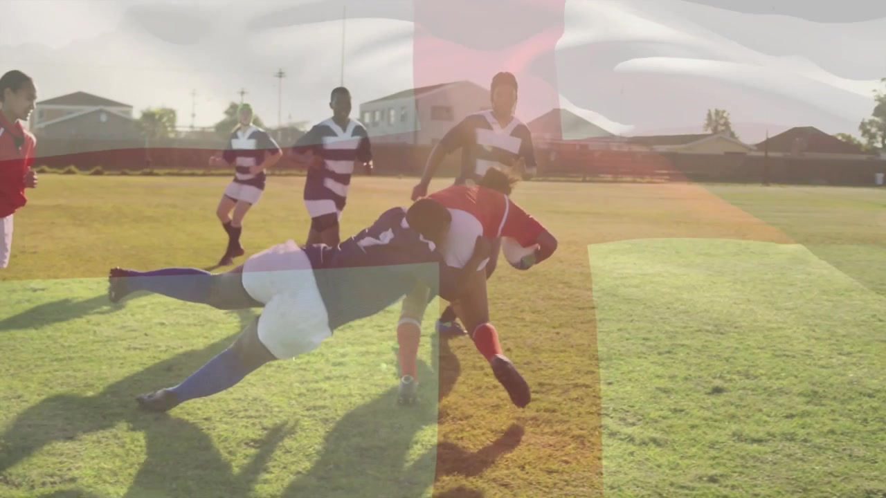 Dospívající hráč rugby s míčem v červeném dresu sprintuje, obránci ho tacklují a spoluhráči bojují o držení míče.