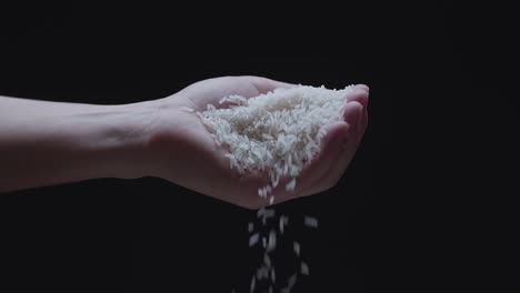 rice grains falling from hand in slow motion  over a dark background