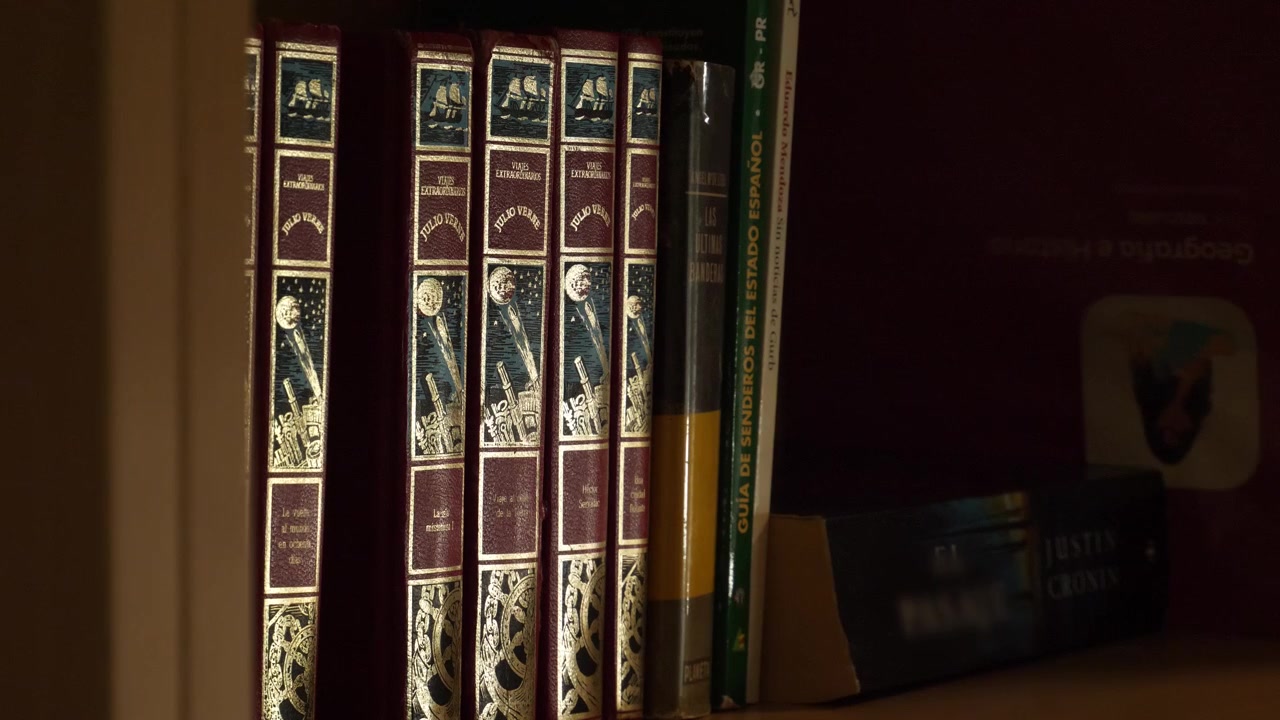 Close-up shot of a hand selecting and taking a classic hardcover book from a crowded home bookshelf, concept for reading, research, literature, and study.