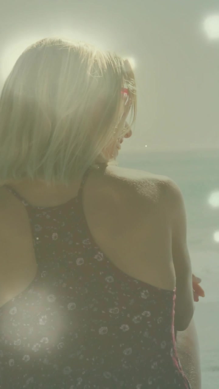 Video verticale: Donna che sente un'amica chiamarla, gira a destra, incrocia le braccia e sorride con occhiali da sole rosa