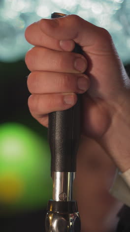 barman turns beer pump lever to pour drink at counter in pub closeup. bartender uses beverage dispenser working in brewery. restaurant employee