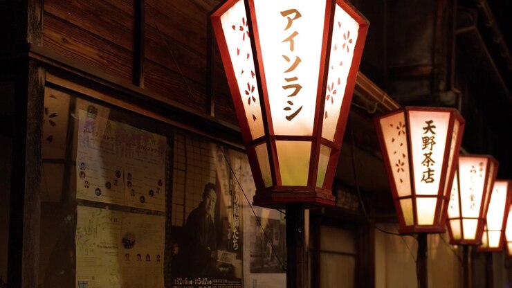 Lanterne di carta tradizionali illuminate appese lungo un edificio in legno di notte a Kanazawa, in Giappone
