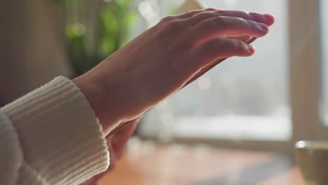 close up of hand flipping page of open book in soft daylight near window, warm ambient light casting glow on paper, coffee mug in background on wooden table