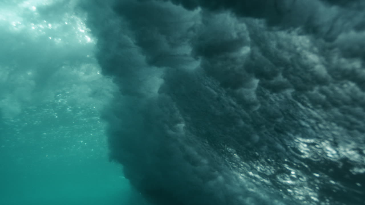 Slow motion underwater of sunlight refracting through gentle wave, fluid textures form