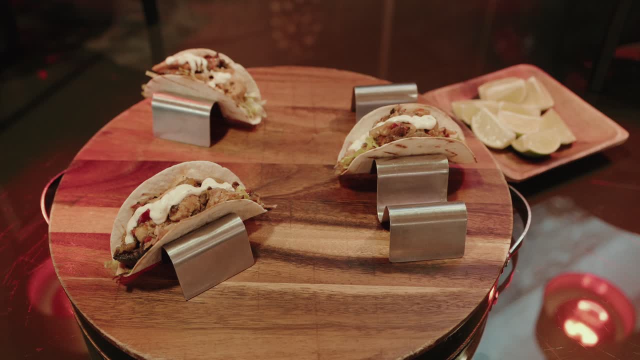 Tacos préparés présentés sur une planche de service en bois avec des quartiers de citron vert