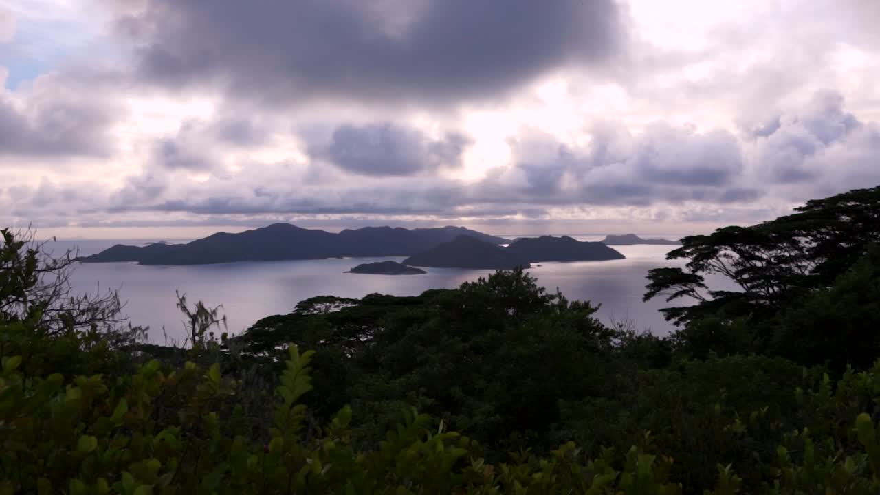 Scenic sunset view on top of a mountain on La Digue, an island in the Seychelles in the Indian Ocean, with some smaller islands in the background